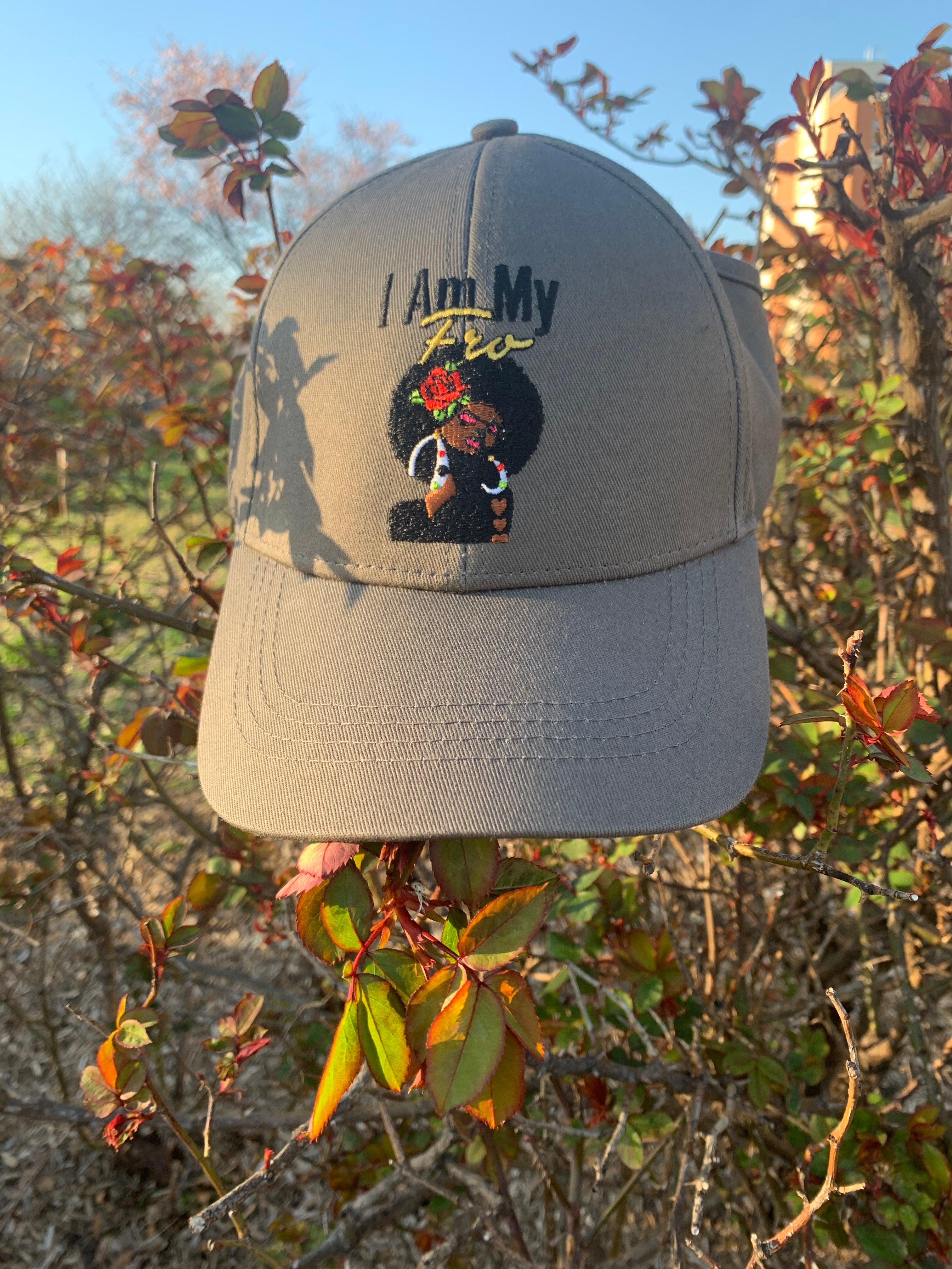 A grey, satin-lined baseball cap shown outdoors near fall foliage.