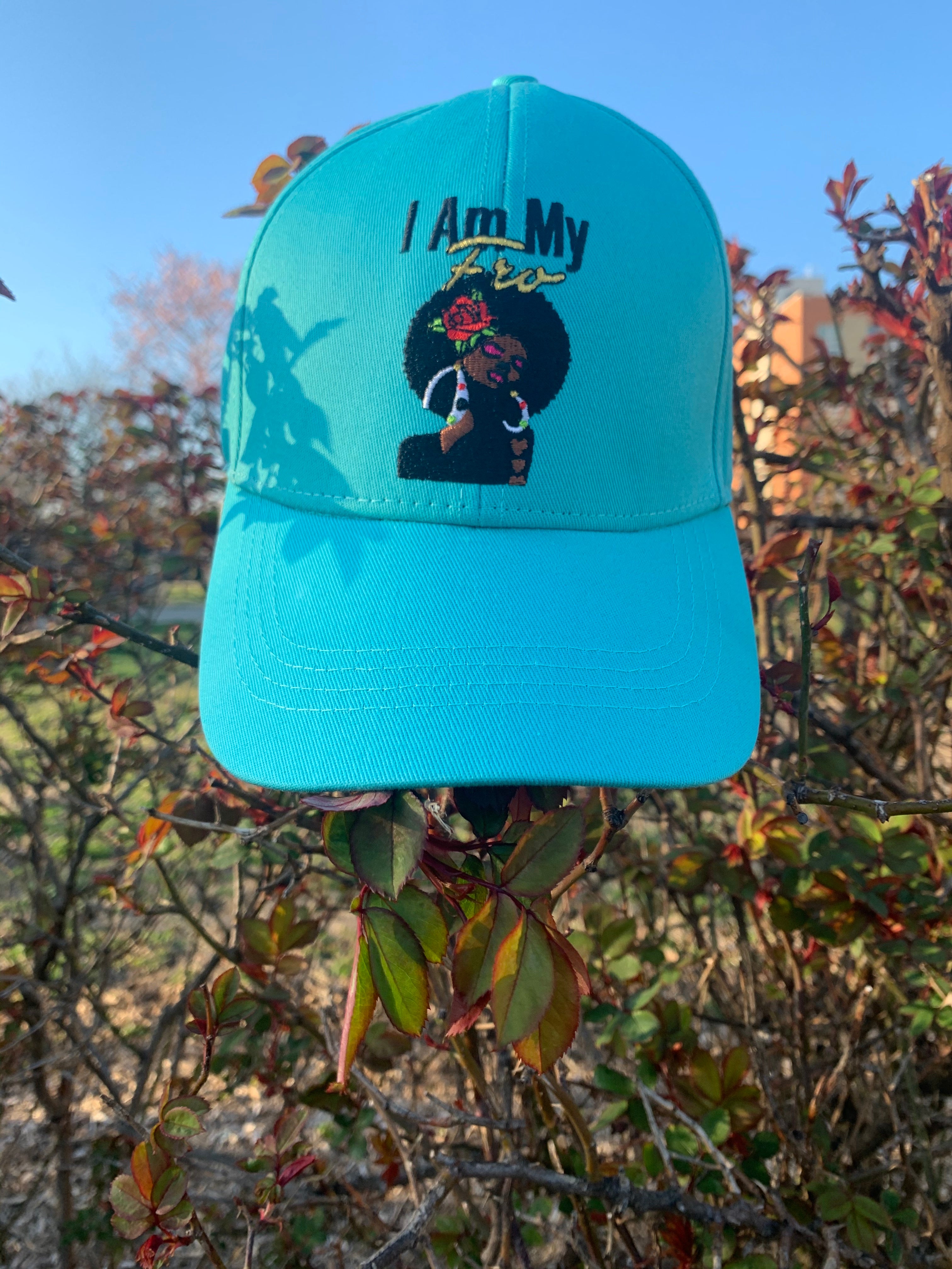 Teal baseball cap facing forward, displayed against a background of fall foliage.